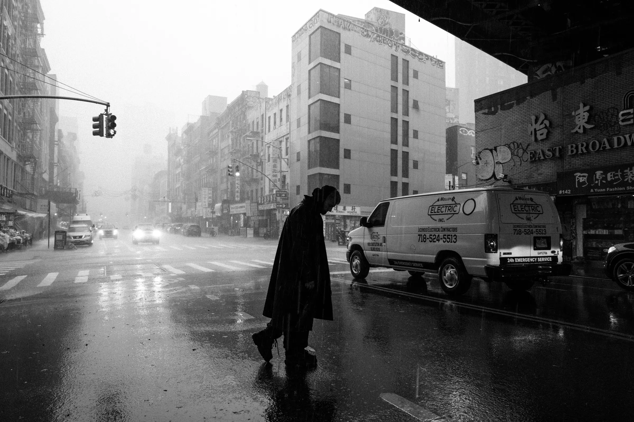 A figure crossing a rain-soaked New York street